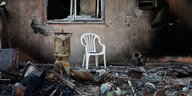 Ein weißer Plastikstuhl steht in einem ausgebrannten, zerstörten Raum