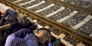 Zwei Männer schlafen neben Bahnschienen