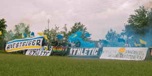 Athletic-Fans am Spielfeldrand mit Transparenten und Pyrofackeln