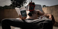 Ein Mann mit Gasmaske liest das Buch "1984" von George Orwell