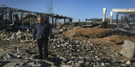 Ein Mann steht auf einem Trümmergrundstück mit zerstörten Gebäudestrukturen
