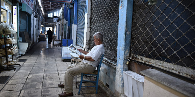 Ein Mann sitzt vor einem geschlossenen Geschäft in Thessaloniki