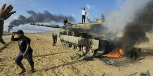Feiernde Palästinenser stehen auf einem zerstörten israelischen Panzer am Zaun des Gazastreifens