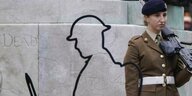 Eine britische Soldatin steht vor einem weissen Bild das nur die Umrisse eines Soldaten zeigt