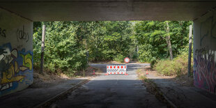 Hinter einer dunklen Autobahnunterführung steht eine rotweiße Absperrung