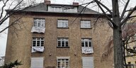 Ein braunes Haus, aus dessen Fenstern weiße Banner hängen, auf denen unter anderem "Jugendhilfe in der Krise!!!" steht