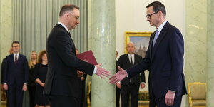 Andrzej Duda (L.) und Mateusz Morawiecki (R.) geben sich bei der Zeremonie zur Ernennung des Premiers die Hand