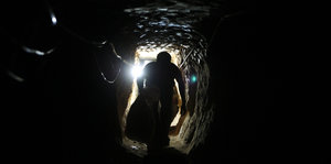 Ein Mann läuft gebückt durch einen engen Tunnel