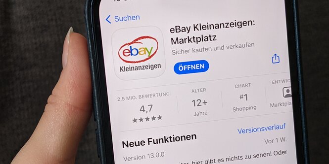 Eine Hand hält ein Handy auf dem die App von Ebay Kleinanzeigen im App Store angezeigt wird.