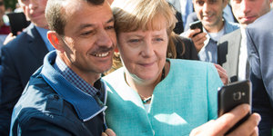 Frau Merkel und ein Flüchtling machen ein Selfie