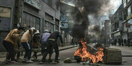 Demonstranten verstärken mit Betonblöcken eine brennende Barrikade in Madagaskars Hauptstadt Antananarivo