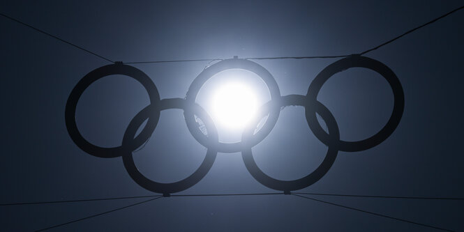 Die tiefstehende Sonne scheint durch einen der fünf Ringe über dem Eingang zum Olympiastadion.