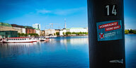 "Hamburg enteignet"-Sticker an einem Laternenmast, die Binnenalster im Hintergrund