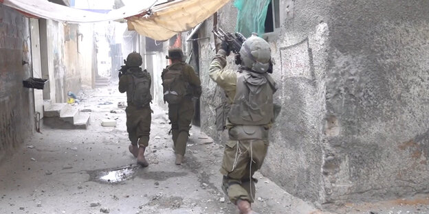 Drei Soldaten in Militärausrüstung und mit Schusswaffen im Anschalg in Gaza