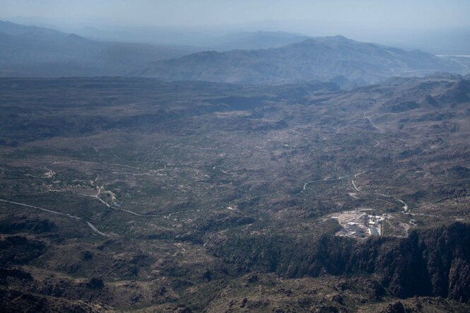 Perspektive von oben aus einem Flugzeug auf das Gebiet Oak Flat, die Landschaft ist hügelig bis bergig mit vielen Bäumen und wenigen Gebäuden