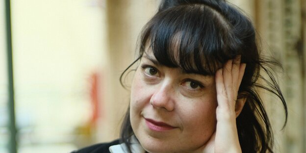 Die Münchner Schriftstellerin Dana von Suffrin sitzt auf einem Stuhl und hält eine Hand an den Kopf
