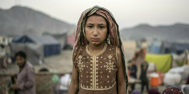 Ein Mädchen in dünnem Sommerkleid in einem Camp für Geflüchtete