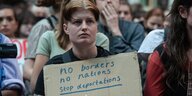 Eine Frau trägt ein Schild mit der Aufschrift "No Borders, no Nations, no Deportations"