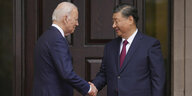 Joe Biden und Xi Jinping beim Handschlag, bei dem Xi die Augen schließt.