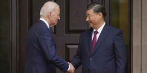 Joe Biden und Xi Jinping beim Handschlag, bei dem Xi die Augen schließt.