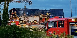 Feuerwehrautos stehen vor einem abgebrannten Gebäude.