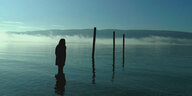 Eine Frau im Gegenlicht am See
