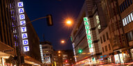 Das Bild zeigt eine Straße, in die auf der einen ein Karstadt-, auf der anderen ein Kaufhof-Schritzug leuchtet.