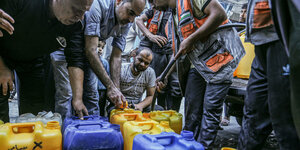 Männer befüllen Wasserkanister mit Trinkwasser