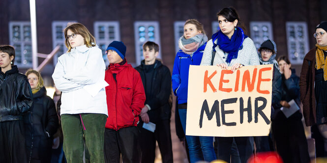 Menschen stehen auf dem Goseriedeplatz in Hannover. Der Schriftzug 