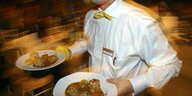 Kellner mit Tellern unt schickem weißem Hemd