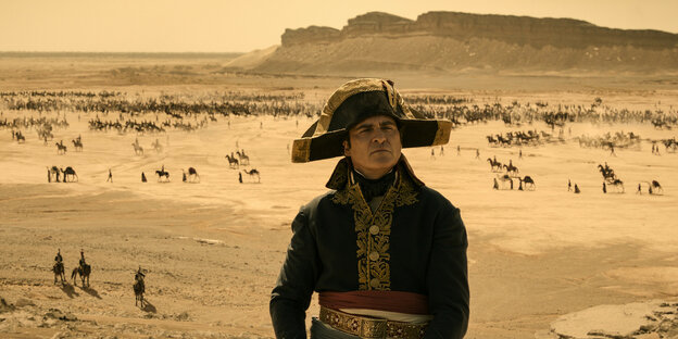 Joaquin Phoenix als Napoleon vor einer Wüstenlandschaft in der Soldaten umherreiten