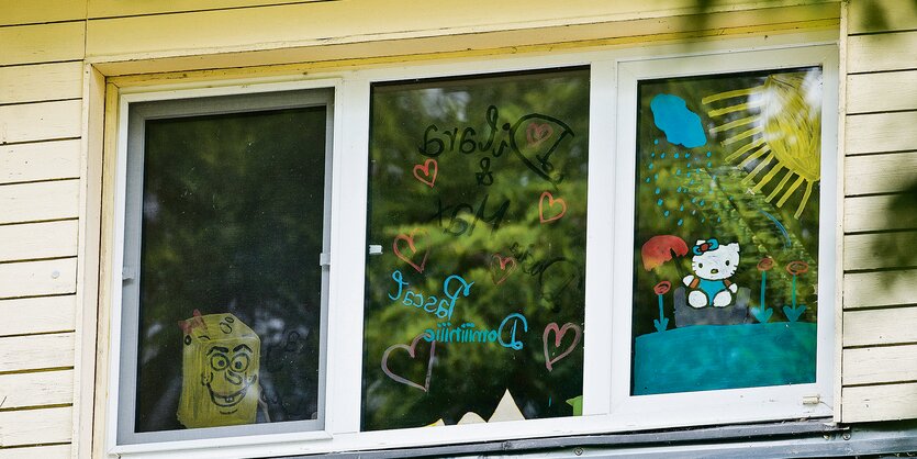 Mit Comic-Figuren bemalte Fensterscheiben neben einer gelben Wand