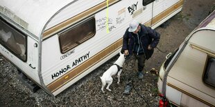 Ein Mann geht mit seinem Hund zwischen zwei Wohnwägen hindurch