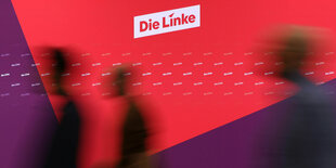 Menschen laufen an einer Wand vorbei, auf der Die linke steht.