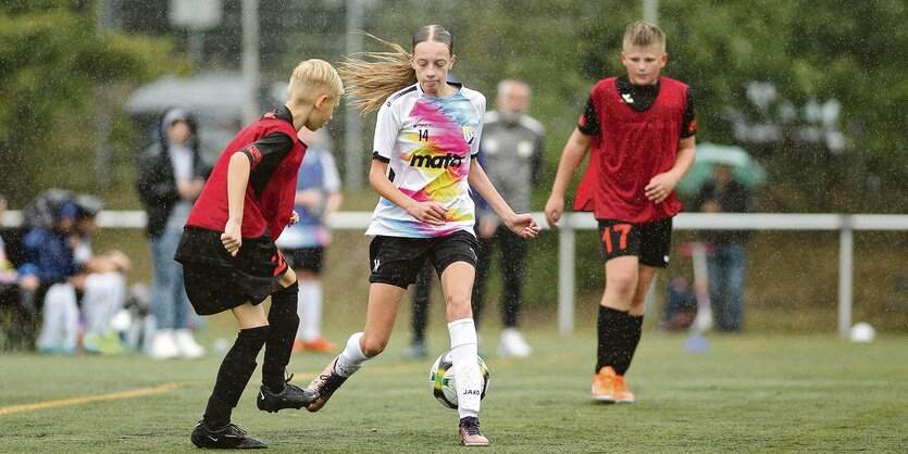 Zwei Jungs und ein Mädchen kämpfen um den Ball