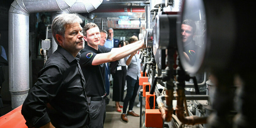 Bundesminister für Wirtschaft und Klimaschutz, läßt sich auf seiner Sommerreise in dem Handwerksbetrieb Temperaturwerk für Heiztechnik von dem Geschäftsführer Marco Goetzke in einem Heizungskeller moderne Heiztechnik erklären.