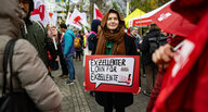 Eine Streikende hält ein Plakat mit der Aufschrift "Exzellenter Lohn für exzellente Studis" hoch