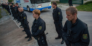 PolizistInnen stehen in einer Reihe, um die ankommenden Flüctlinge zu beschützen.