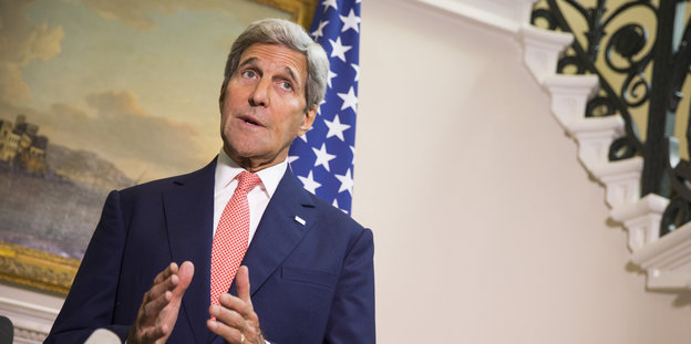Kerry steht vor einer USA-Flagge und redet zur Presse