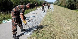 An der Grenze zu Kroatien verlegen Soldaten Stacheldraht.
