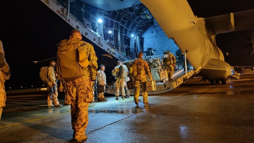 Bundeswehrsoldaten laufen auf ein Flugzeug zu. Sie sind bepackt mit Ausrüstung und schweren Rücksäcken