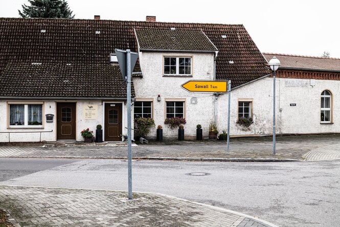 Dorfstraße mit Häusern und gelbem Straßenschild