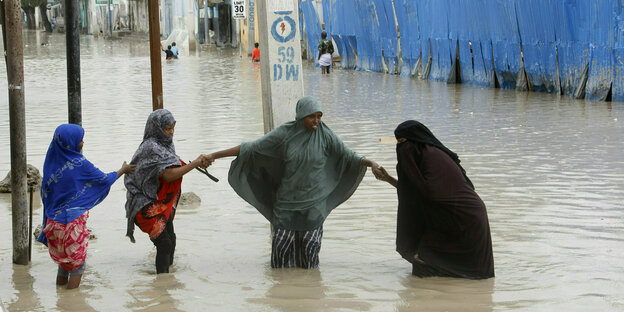 4 Frauen versuchen in Mogadischu eine überflutete Straße zu überqueren