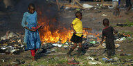Kinder spielen in der Nähe eines Feuers in Mbare, einem Armenviertel in Harare, Simbabwe