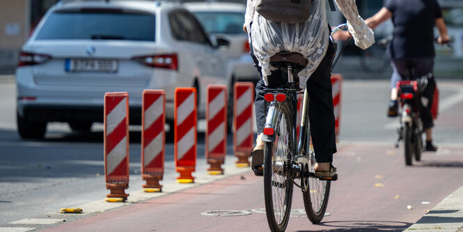 Radfahrende neben kleinen orangenen Pollern (Leitboys)