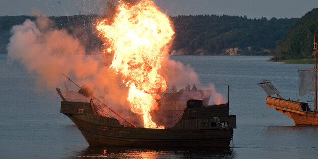 Ein brennendes Segelschiff auf dem Wasser