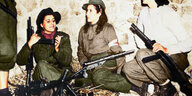 Vier Frauen mit Maschinengewehren rauchen gemeinsam.
