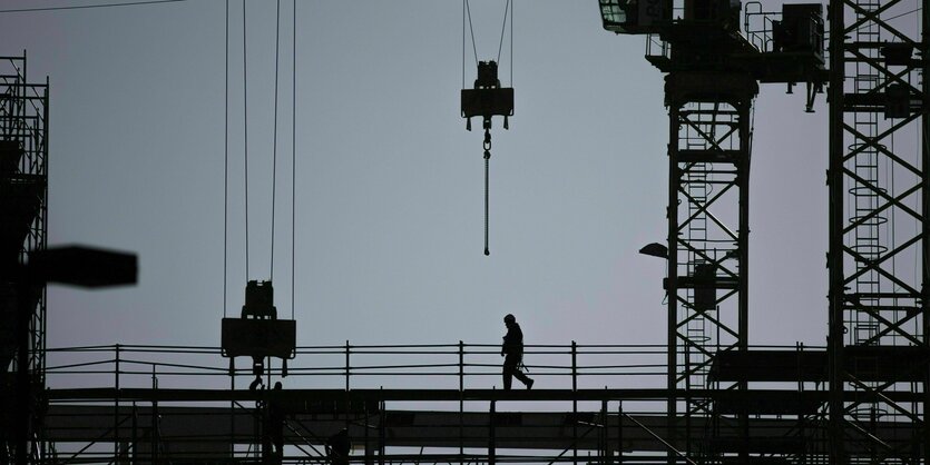 Der Schattenriss eines Geruestbauers zeichnet sich auf einer Baustelle ab in Berlin