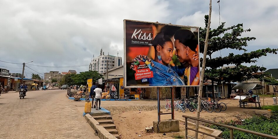 Straßenszene in Cotonou, Benin mit einem Plakat, auf dem für Kondome geworben wird