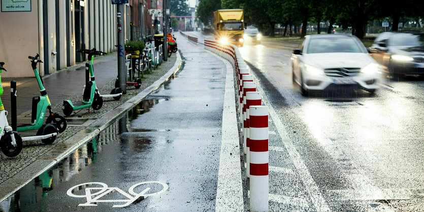 Eine befahrene Straße mit Radweg im Regen.